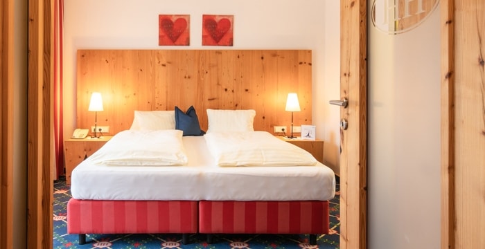 Blick durch geöffnete Holztür ins Schlafzimmer der Junior Suite mit Doppelbett