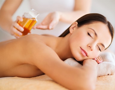 Masseurin kippt Massageöl über Rücken von Frau